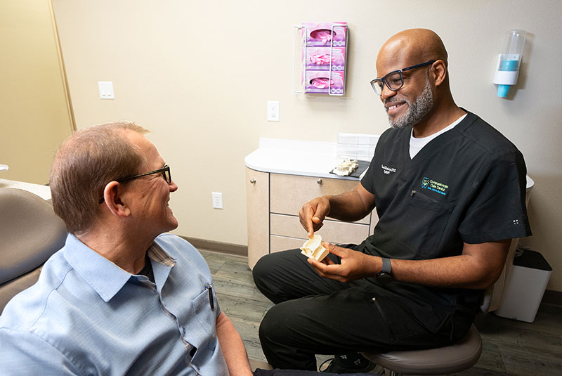 Dr. Dawud Muhaimin showing patient a model of dental implants